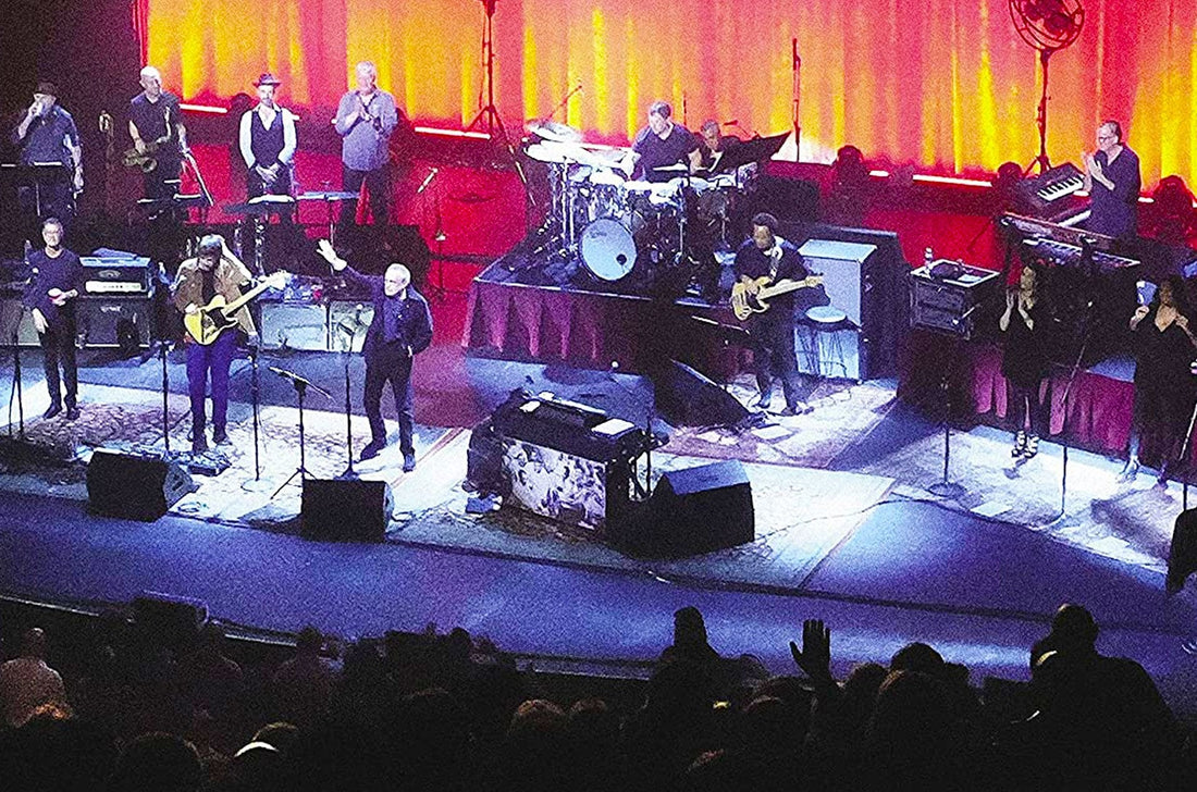 Photo of the cover from the Steely Dan New Live Album and Limited Edition Vinyl. The image features a photo of the band playing on a black stage in front of orange curtains.