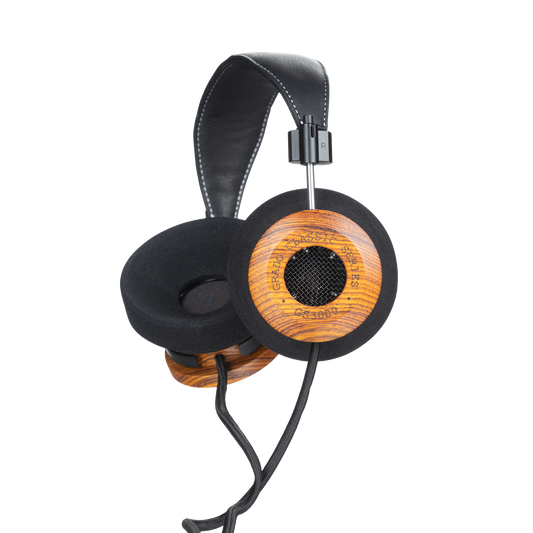 Photo of Grado GS3000 Headphones on a white background taken from the 3/4 view - One ear cup is facing down while the other ear cup is facing outward - the words - Grado Classic Series - and - GS3000 - can be seen on the ear cup.
