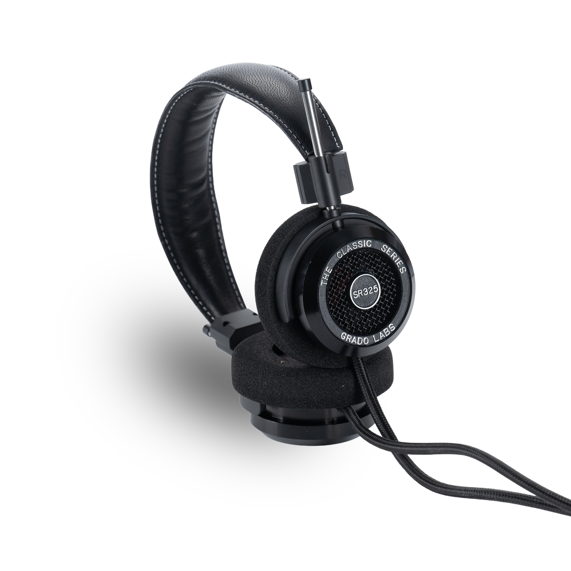 Photo of Grado SR325 Headphones taken from the 3/4 view - One ear cup is facing down while the other ear cup is facing outward - showing the model name in the center - SR325 - and the words - The Classic Series - and - Grado Labs - written along the edge of the ear cups.