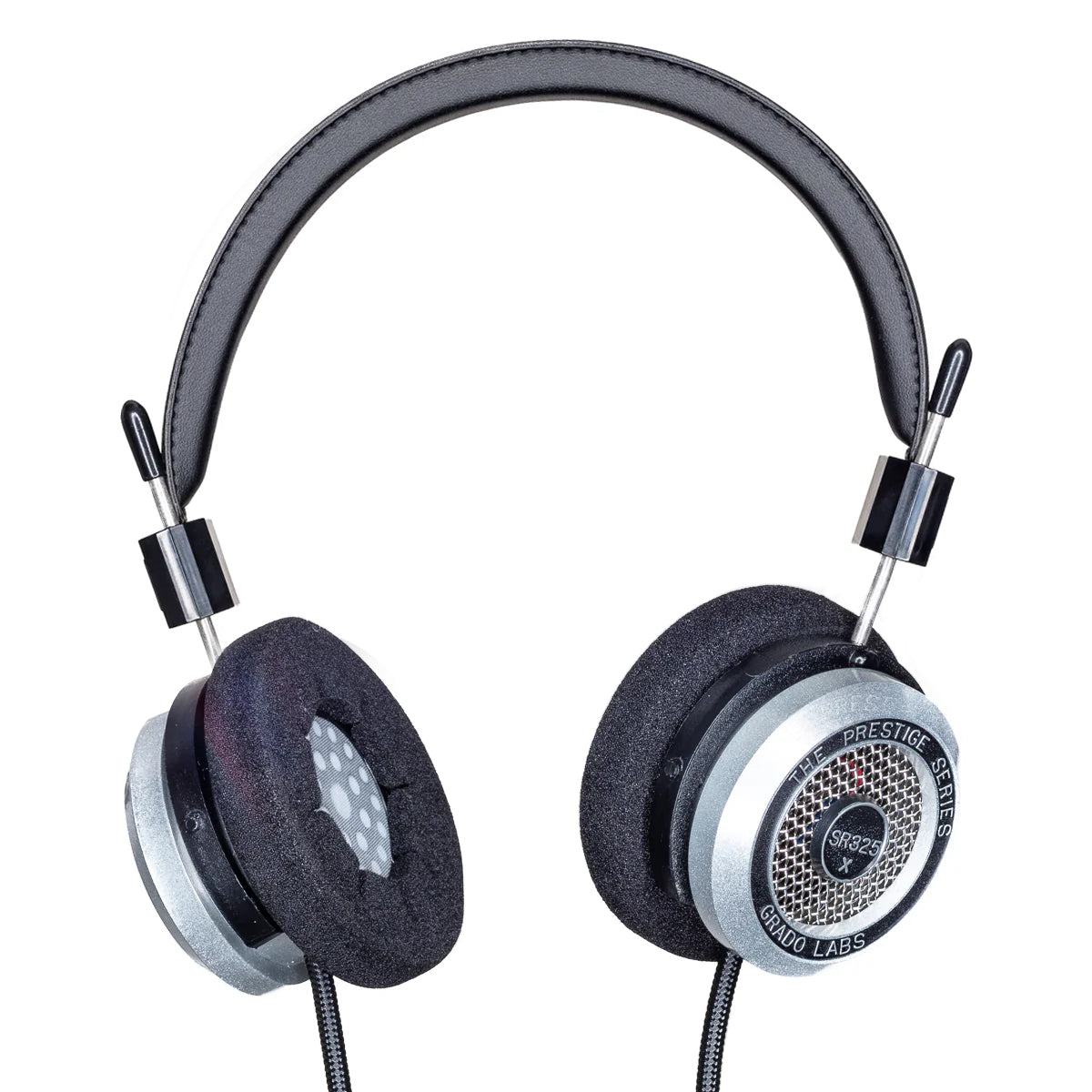 Photo of Grado SR325x Headphones  taken from 3/4 view - one ear cup is facing away from view while the other is showing the model name - SR325x - can be seen in the center and the words - The Prestige Series - and - Grado Labs are written on the outside edge of the ear cups. The cables can be seen coming out of the headphone.