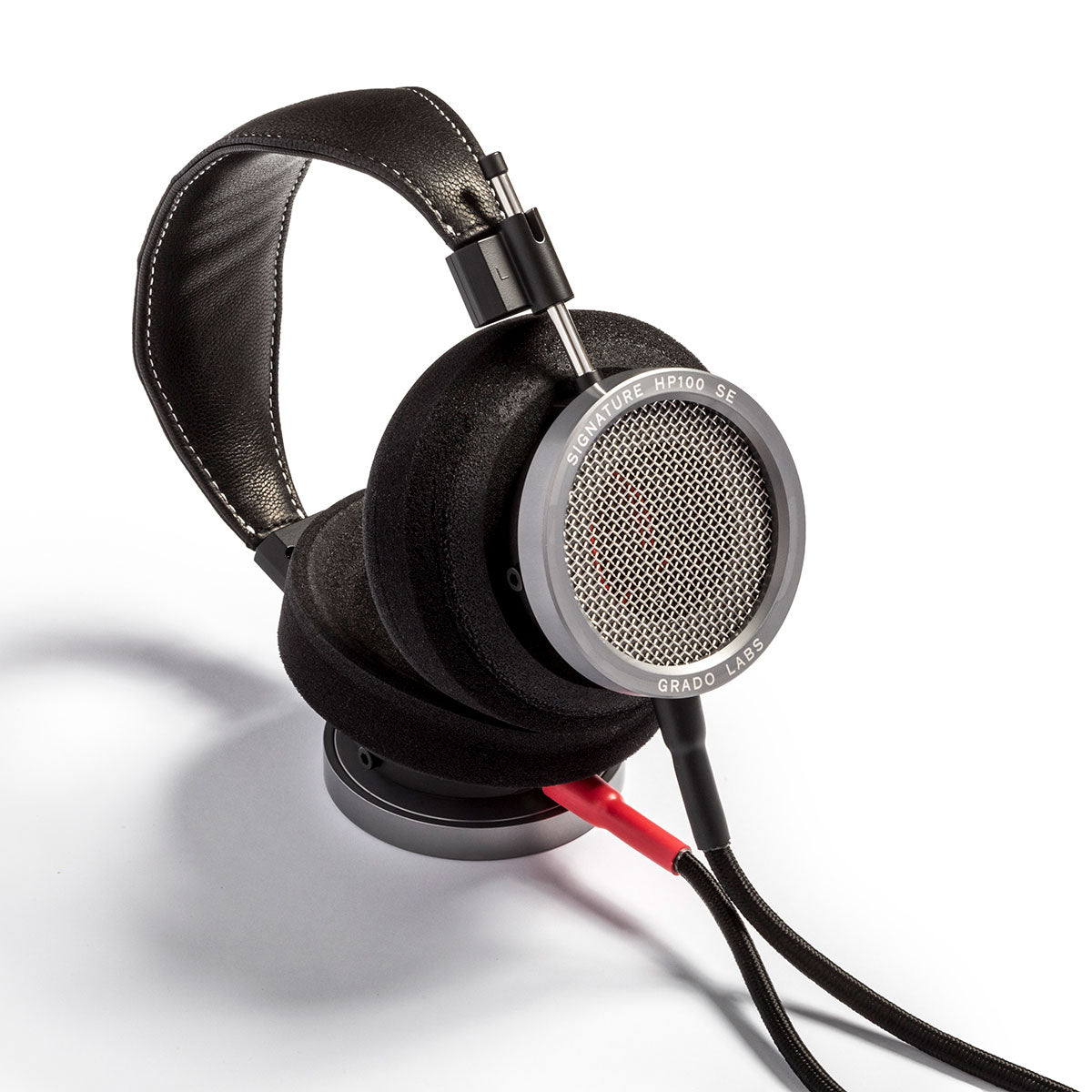 Photo of Grado HP100 SE Headphones taken from the 3/4 view - One ear cup is facing down while the other ear cup is facing outward - the words - Grado Labs - and - HP100 SE - can be seen on the ear cup.