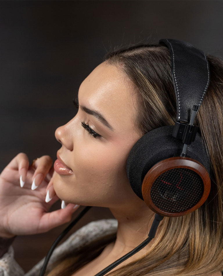 Photo of a woman wearing Grado S950 Headphones while holding her hand on her chin.