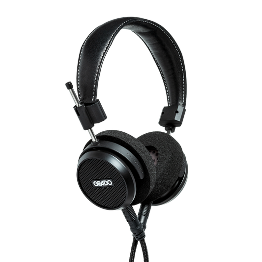Photo of Grado S150 Headphones taken from the 3/4 view - the Grado logo is featured in the center of the ear cup and the black cables can be seen coming out of the headphone.