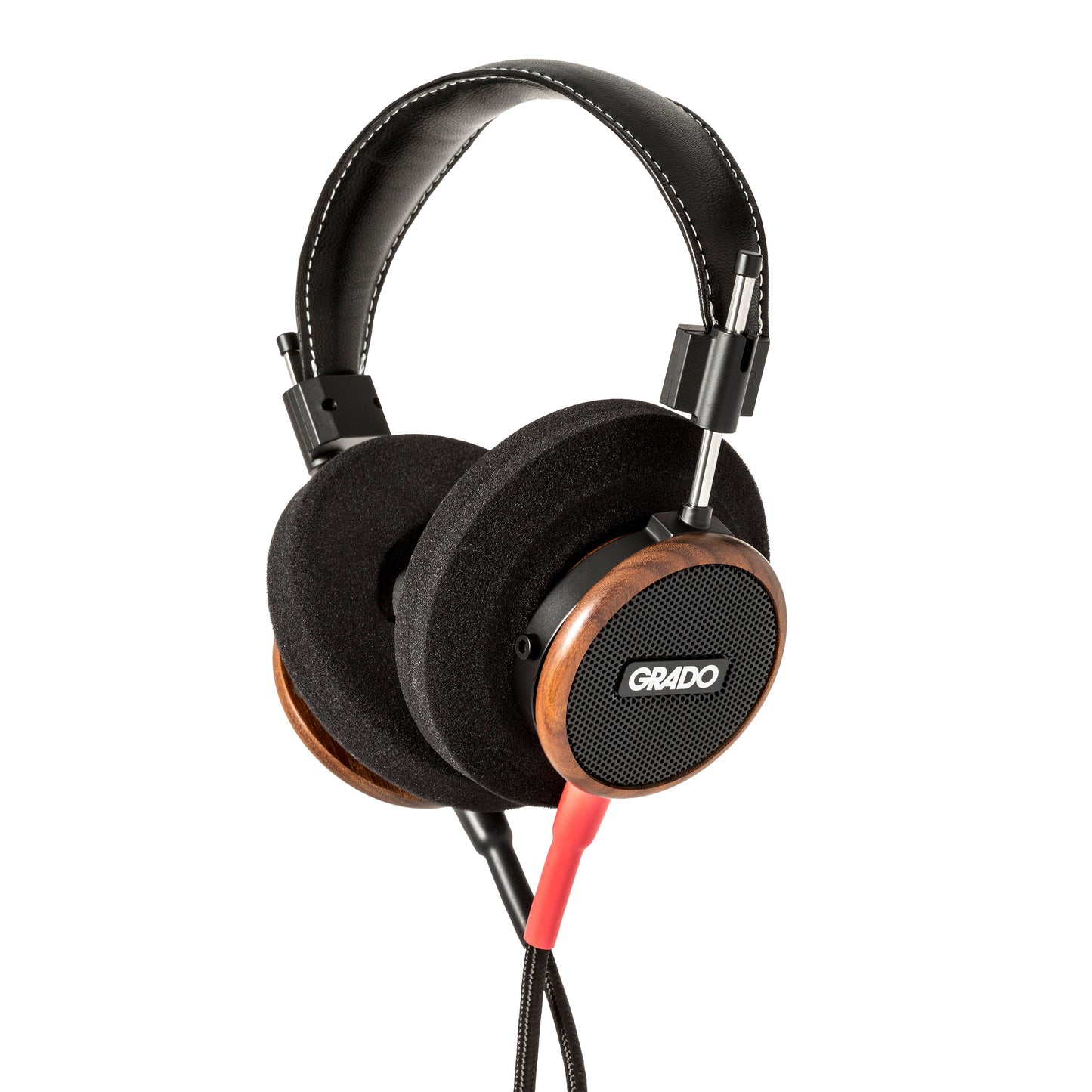 Photo of Grado S550 Headphones on a white background taken from 3/4 view - one ear cup is facing away from view while the other is showing the Grado logo in the center. The red/black cables can be seen coming out of the headphone.