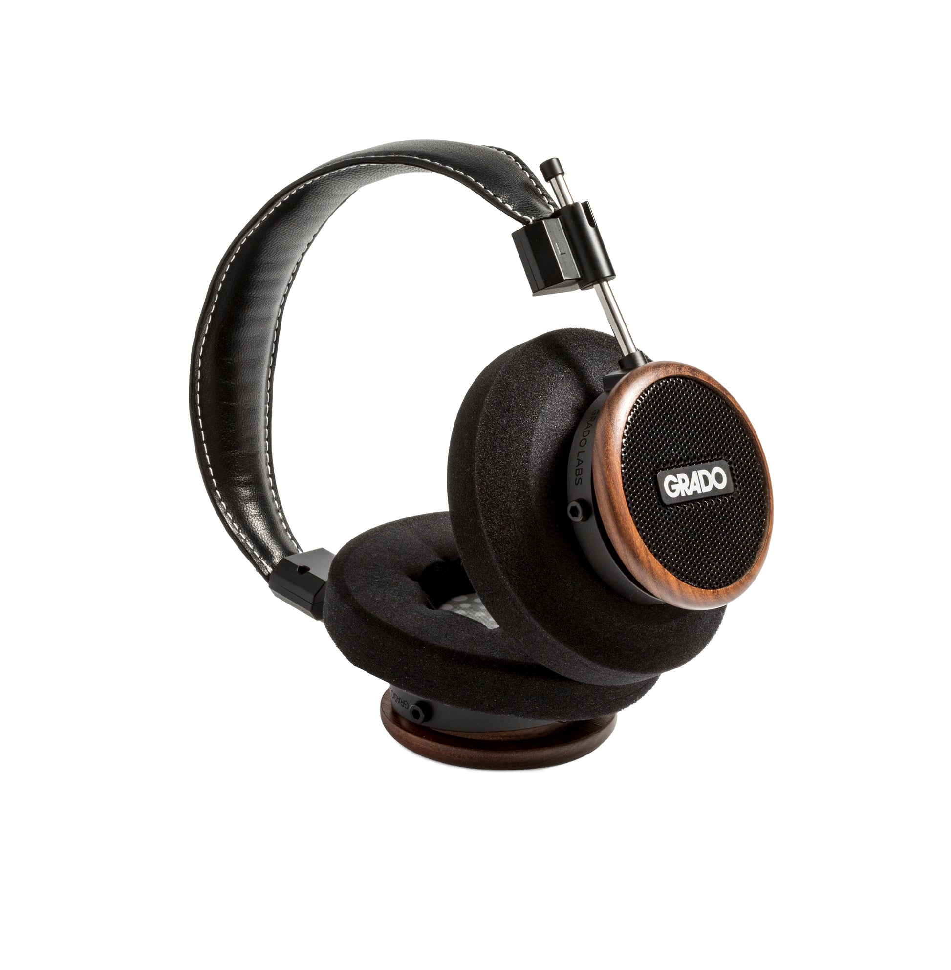 Photo of Grado S550 Headphones on a white background taken from the 3/4 view - One ear cup is facing down while the other ear cup is facing outward - showing the Grado logo.